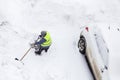 Worker shoveling snow near cars on parking. Top view