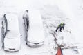 Man shoveling snow near cars on parking. Top view of snow clearance