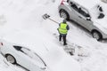 Man shoveling snow after snowfall on parking near car