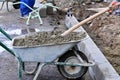 Worker shovels concrete from a wheelbarrow at curb block installation. Royalty Free Stock Photo