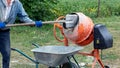 A worker shovels sand into a concrete mixer, preparing cement mortar Royalty Free Stock Photo