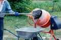 A worker shovels sand into a concrete mixer, preparing cement mortar Royalty Free Stock Photo