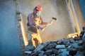 Worker with sledgehammer at indoor wall destroying