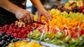 A worker slicing fresh fruits for a fruit salad with different colored fruits arranged in an eyecatching display Royalty Free Stock Photo