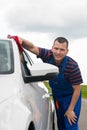 Worker smiles and wipes the car with a red rag Royalty Free Stock Photo