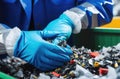 Worker sorts electronic waste for recycling, wearing blue gloves for protection Royalty Free Stock Photo