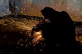 Worker and sparks of bonfire while grinding iron