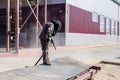 A worker in a special suit is sandblasting metal at an industrial site