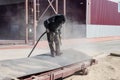 A worker in a special suit is sandblasting metal at an industrial site