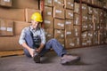 Worker with sprained ankle on floor in warehouse Royalty Free Stock Photo