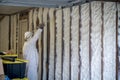 Worker spraying closed cell spray foam insulation on a home wall