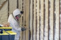 Worker spraying closed cell spray foam insulation on a home