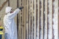 Worker spraying closed cell spray foam insulation on a home