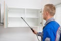 Worker Spraying Insecticide On Shelf