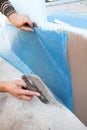 Worker spreading mortar over styrofoam insulation with trowel.