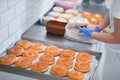 A worker sprinkles donuts with crumbled biscuits in a candy workshop. Pastry, dessert, sweet, making