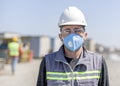 The worker staff, engineer protects himself from covid-19 coronavirus with a protective mask in the construction site. Royalty Free Stock Photo