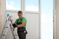 Worker standing on folding ladder indoors. Window installation Royalty Free Stock Photo