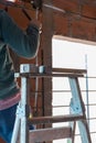 Worker standing on a ladder and breaking the wall with chisel in a construction site Royalty Free Stock Photo