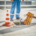 Worker standing next to open sewer manhole near traffic cone. Repair of sewerage and underground communications