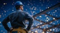 Worker stands confidently at construction site, watching bright sparks fly during welding operation at night. Setting Royalty Free Stock Photo