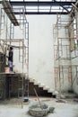 Worker stands on the steel scaffolding and plastering the cement