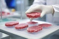 Worker in sterile gloves putting pieces of lab-grown meat on counter