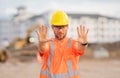Worker with stop hand gesture. Builder in a hard hat working on a construction project at a site. A builder worker in a Royalty Free Stock Photo