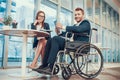 Worker in wheelchair with tablet in office.