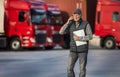 Worker talking on phone in front of trucks