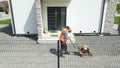 Worker tamping the driveway in front of a house with vibratory plate machinery. Royalty Free Stock Photo