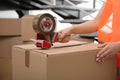 Worker taping cardboard box indoors, closeup view