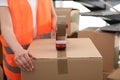 Worker taping cardboard box indoors, closeup view