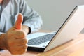 The worker thumbs up working with laptop in office