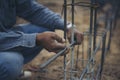 Worker ties wire metal steel to building structure at construction site. Man hand holding material Metal Steel reinforced rod for Royalty Free Stock Photo