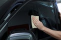 Worker tinting car window with foil in workshop