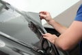 Worker tinting car window with foil in workshop