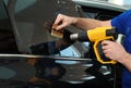 Worker tinting car window with heat gun in workshop, closeup