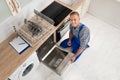Worker With Toolbox Repairing Dishwasher Royalty Free Stock Photo