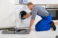 Worker With Toolbox Repairing Washing Machine