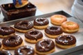 A worker is topping donuts with chocolate topping in a candy workshop. Pastry, dessert, sweet, making