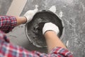 Worker with trowel mixing concrete in bucket indoors, closeup