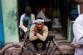 Worker in a turban rests leaning on his retro bicycle on the street