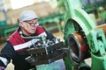 worker turner operating lathe machine at industrial manufacturing factory