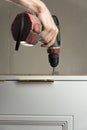 A worker twists a screw into the Board with a drill. The handyman does housework and improves the dwelling. Photographed