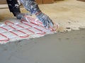 A worker unfolds a roll of warm electric floor for laying under a cement screed Royalty Free Stock Photo