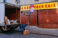 A worker unloading a truck in front of a restaurant in Chinatown