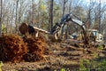 Worker uproots trees in forest with help of an by using excavator, preparing ground for a house construction