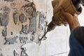 Worker use demolition hammer drill to break up tiles from wall surface. Motion blur intended.