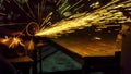 the worker uses cutting machine to cut metal, focus on flash light line of sharp spark,in low Light Royalty Free Stock Photo